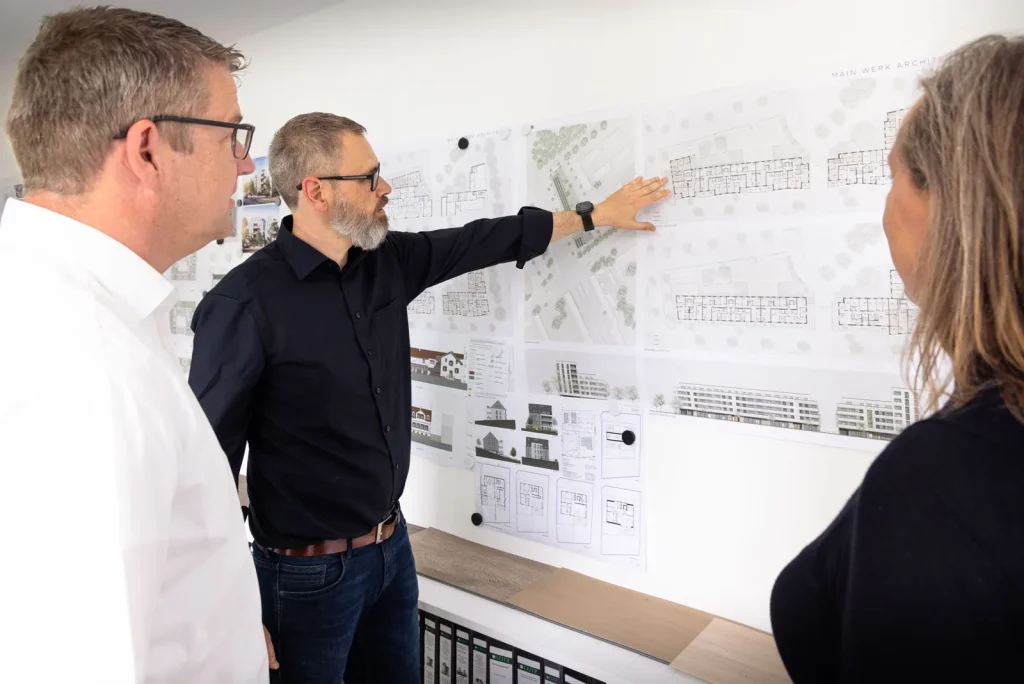 Architekten von Main Werk besprechen Pläne an der Planwand im Büro